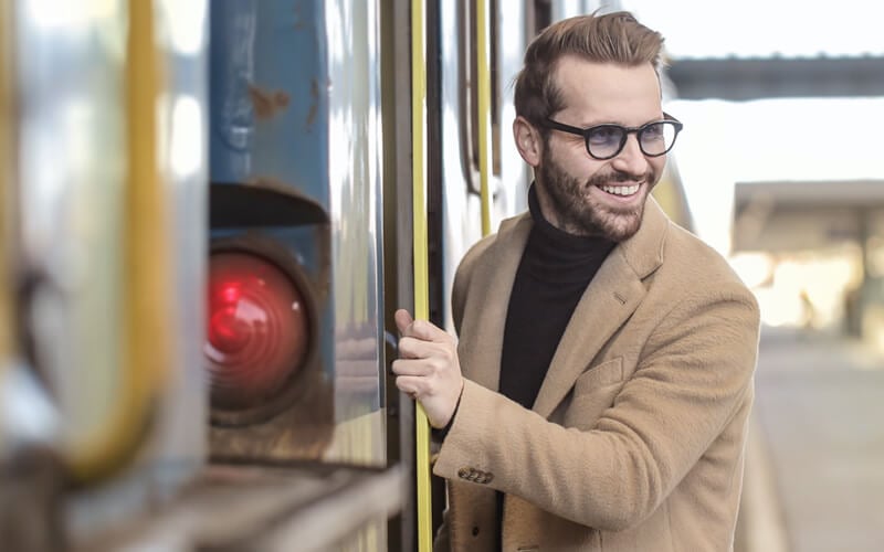 Man with glasses getting into a vehicle and smiling behind him
