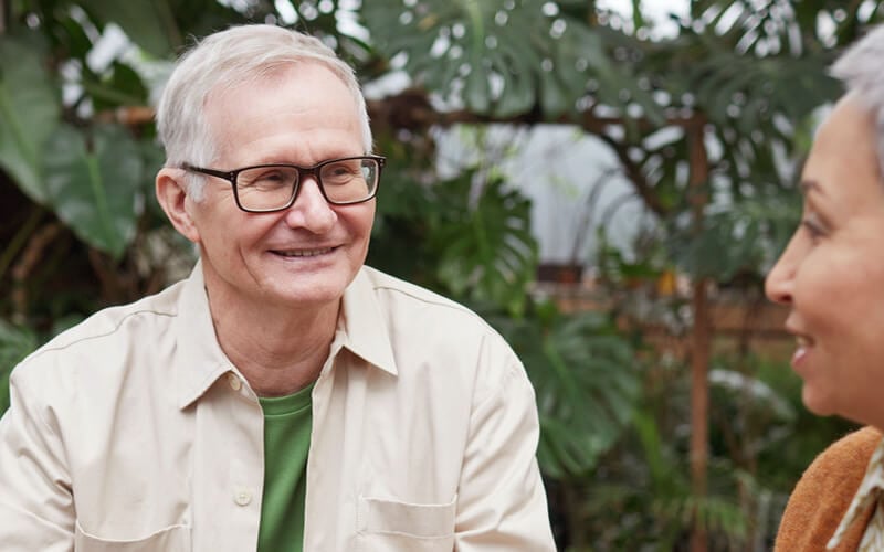 Man with grey hair and glasses smiling at a woman just out of shot
